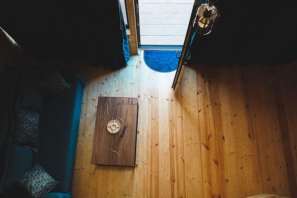 A wooden interior with a door, a blue mat, and a ceiling light fixture. - Cottage Luno (Kazbegi)