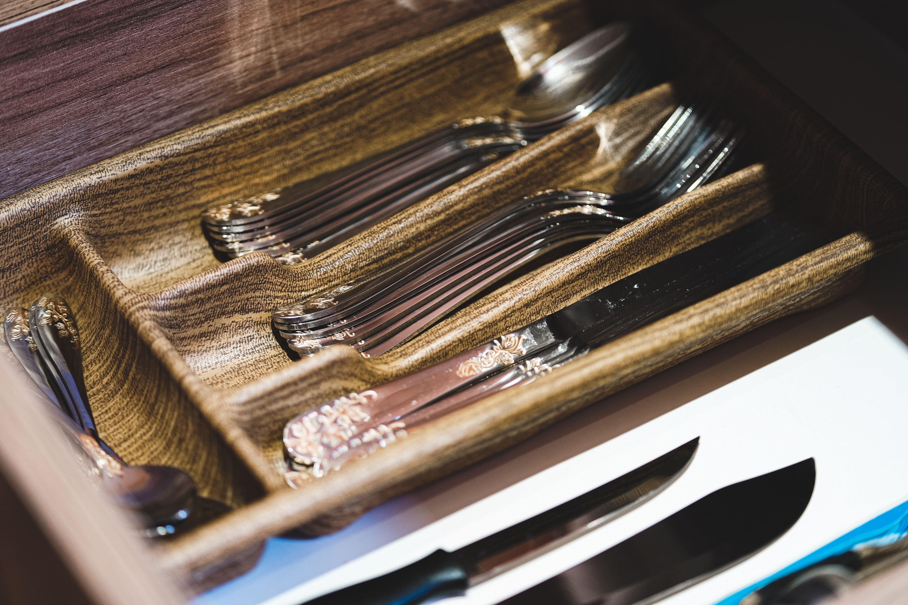 Un plateau en bois contenant des couverts, notamment des fourchettes, des couteaux et des cuillères.