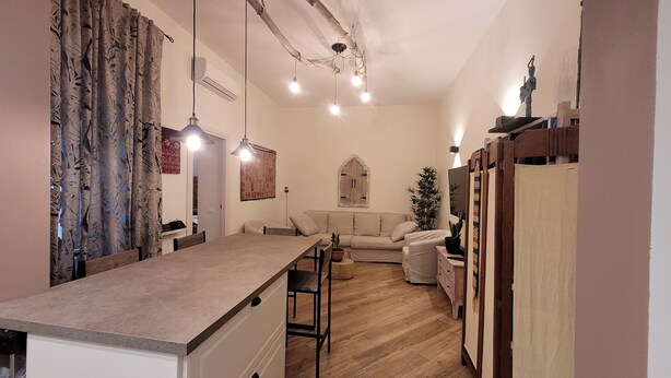 Une cuisine chaleureuse avec un coin repas, un plancher en bois et un luminaire suspendu.