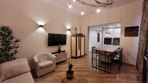 Un salon moderne comprenant un canapé, un téléviseur et un coin repas avec une table et des chaises.