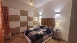Une chambre à coucher comprenant un lit, des tables de chevet, un luminaire suspendu et une tête de lit décorative.