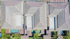 A modern hotel with a geometric roof design, multiple swimming pools, and lush landscaping.