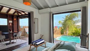 Een kamer met een bed, een bureau en uitzicht op een zwembad en een terras.