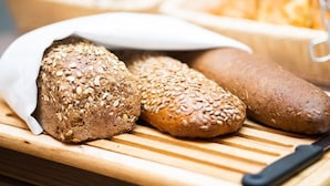 Three loaves of bread on a wooden cutting board. - Hotel Orangerie (Vienna)