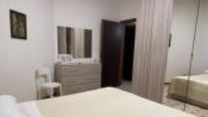 A hotel room with a large bed, a dresser, a chair, and a mirror on the wall. - Cozy and lovely apartment, a stone's throw from the sea and 200mt from the center. (Maiori)