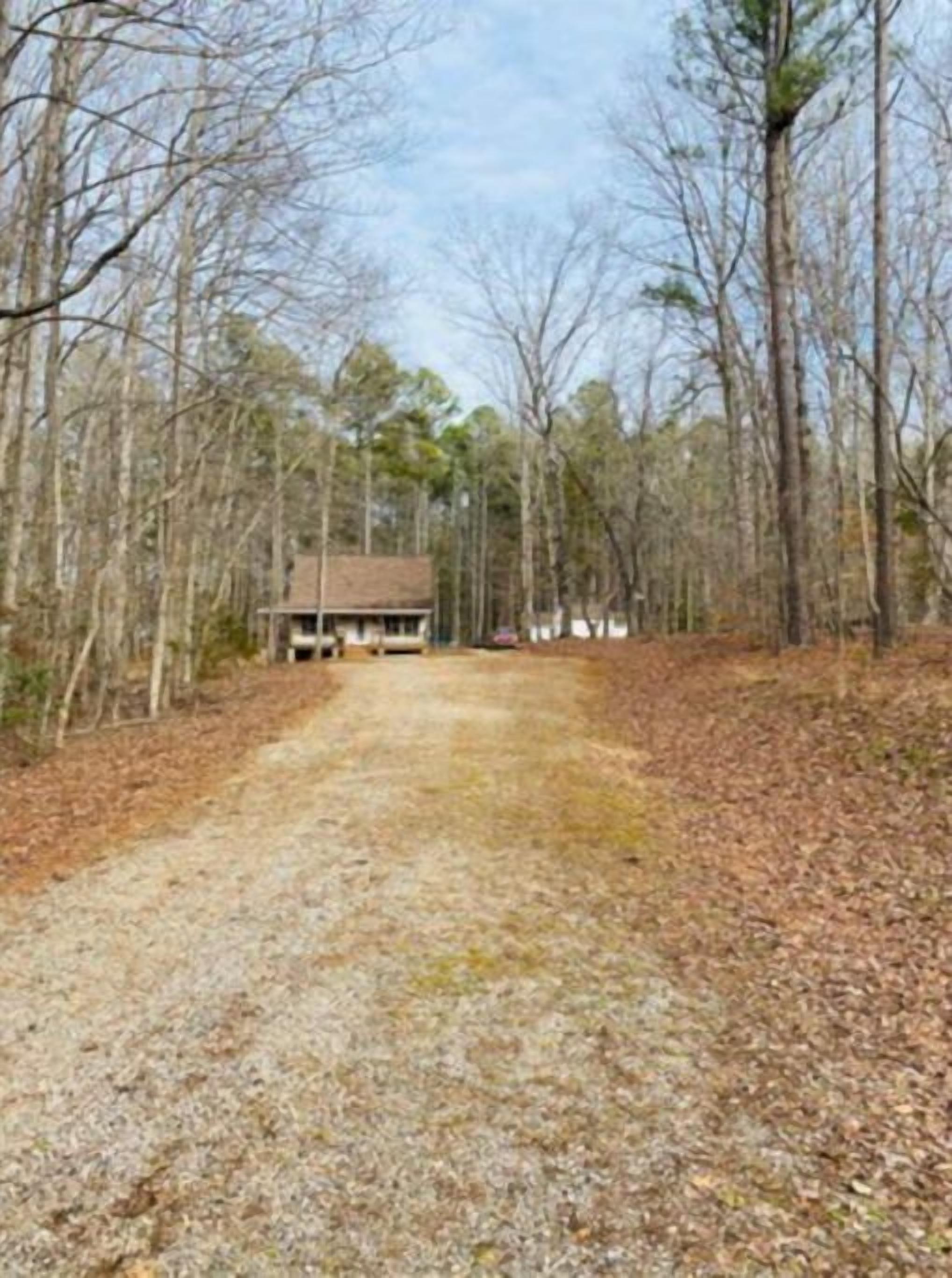 Un chemin de gravier mène à un chalet en bois entouré d’arbres.
