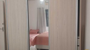 Una camera da letto con armadio a scorrimento, un letto con lenzuola rosa e una ventola a soffitto.