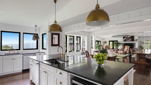 A spacious kitchen with a large island, white cabinetry, and pendant lighting. - Paradise Found. The Ultimate Skaneateles Lake Retreat. (Skaneateles)