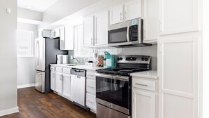 Een moderne keuken met witte kastjes, roestvrijstalen apparatuur en een donker houten vloer.