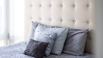Una cama con cabecera capitonada y muchas almohadas.