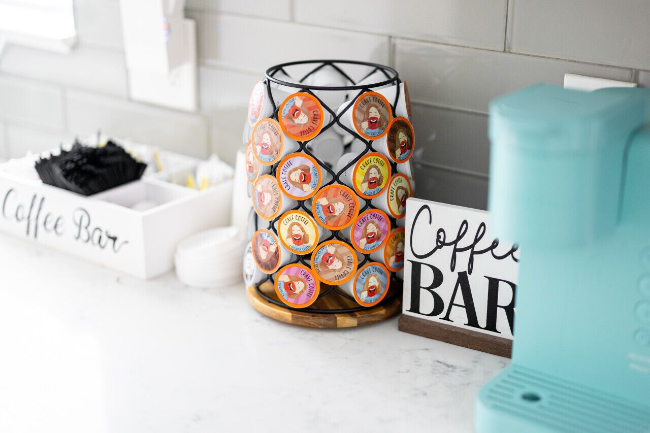 Un espacio de cafetería con un recipiente decorativo que contiene cápsulas de café y un letrero que dice 'Coffee Bar'.