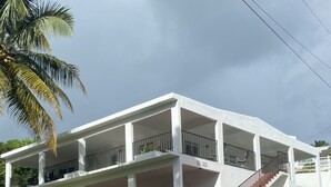 A white multi-story building with balconies and a staircase leading to the upper floors.