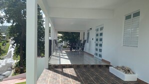 A covered outdoor area with a tiled floor, a seating arrangement, and a view of the street.