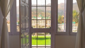 Una habitación con un ventanal grande, cortinas y piso de madera.