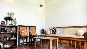 Una sala de estar con un sofá, dos sillas de madera, una mesa de centro, una estantería y un tapete estampado.