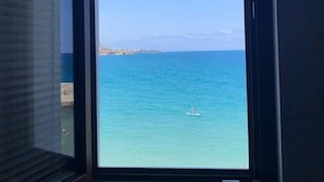 Une pièce dotée d’une grande fenêtre donnant sur une mer calme et une côte lointaine.