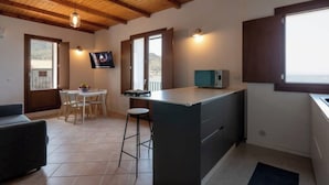 Une cuisine compacte avec un coin repas, des poutres en bois au plafond, un téléviseur et une vue par la fenêtre.