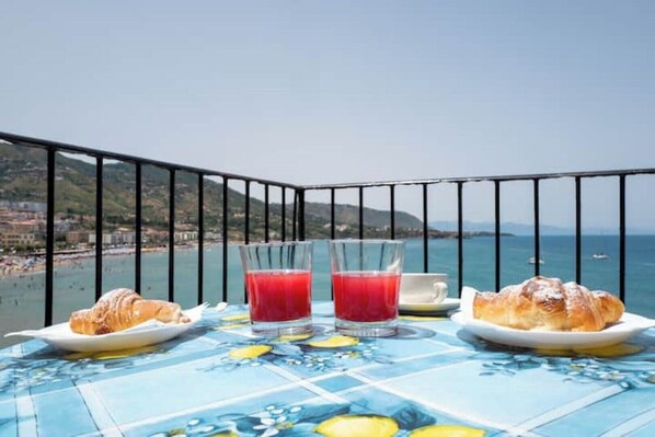 Ein Balkon mit Frühstückstisch und Blick auf die Küste.