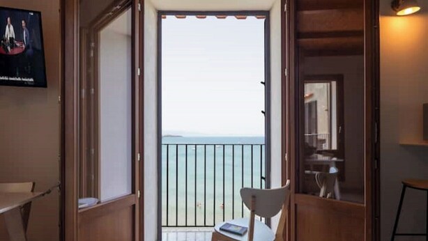 Une chambre avec vue sur la mer, une chaise, une table et un téléviseur fixé au mur.