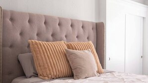 Ein Schlafzimmer mit einem gepolsterten Kopfteil, einem großen Bett mit weißer Steppdecke und zwei Kissen.