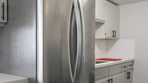 Eine moderne Küche mit Edelstahlgeräten, weißen Schränken und Holzboden.