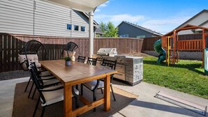 An outdoor patio with a wooden table and chairs, a grill, and a wooden play structure. - Prestine and Comfortable Home (Brush Prairie)