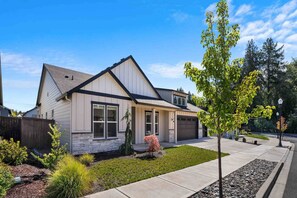Stunning single-family home with a central entrance, flanked by two windows, set amidst a beautifully manicured lawn and lush greenery.