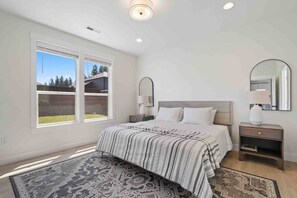 Relax in this serene bedroom with a large bed, nightstands, and a window offering a view of the outdoors.