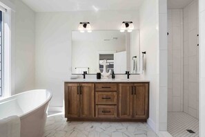 Features a bathtub, double vanity, and walk-in shower in a serene and functional space.