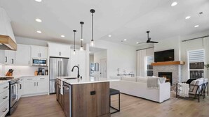 A modern kitchen with white cabinets, a central island, and pendant lighting. - Prestine and Comfortable Home (Brush Prairie)