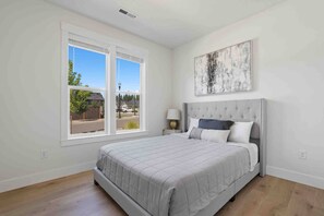 A bedroom with a bed, a window, a nightstand, and a wall-mounted artwork. - Prestine and Comfortable Home (Brush Prairie)