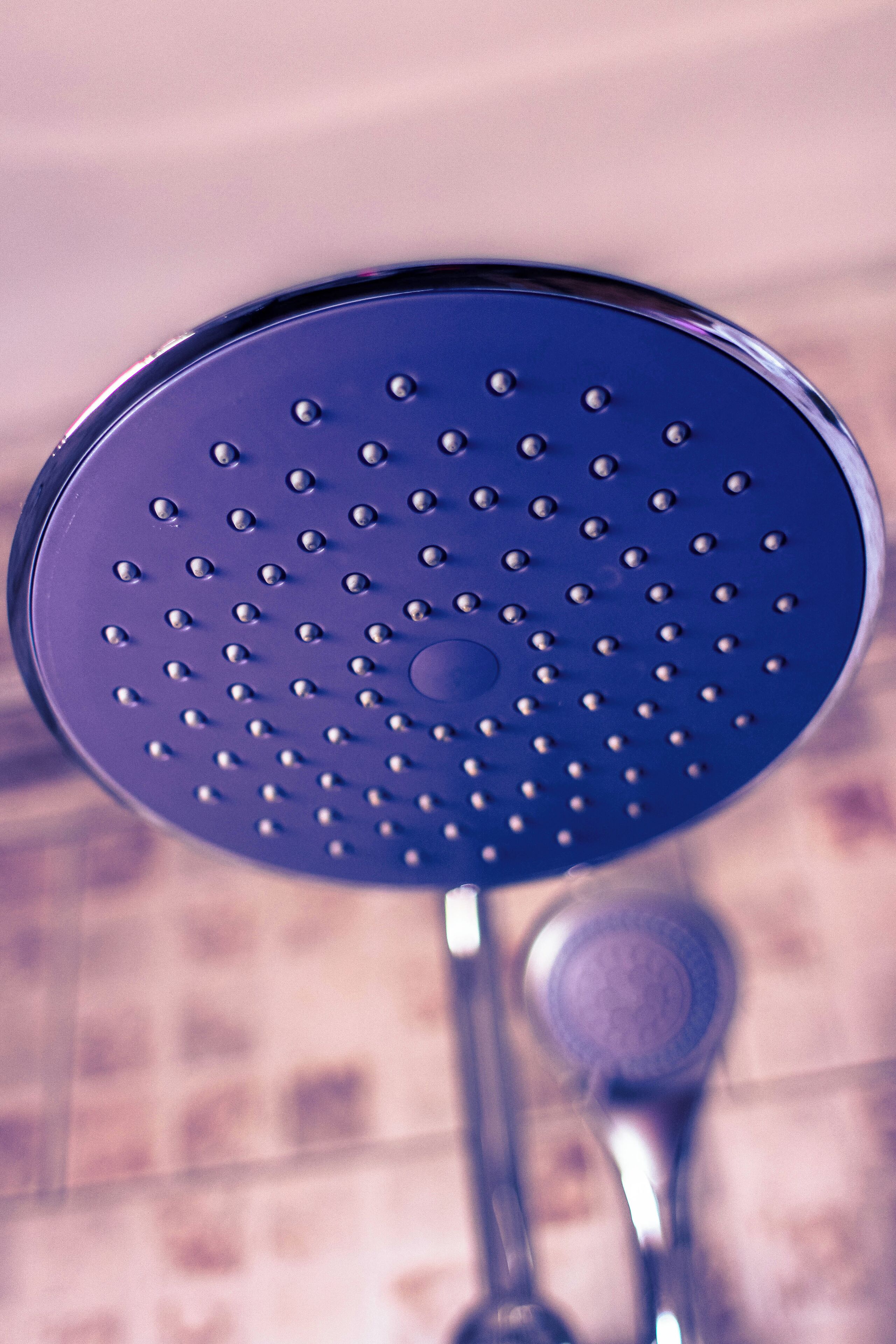 A close-up of a showerhead with a circular design and multiple holes.