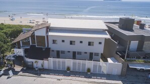 Un edificio costero con terraza con vistas a la playa, un letrero que indica un restaurante y una entrada con portón.