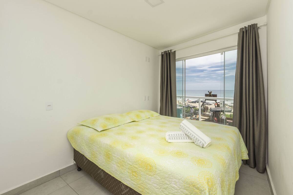 Un cuarto de hotel con una cama, una ventana con cortinas y vista a la playa.
