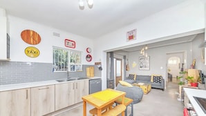Une cuisine moderne avec des meubles en bois, une table jaune et un banc. On y trouve un coin repas avec un canapé gris et une table basse.