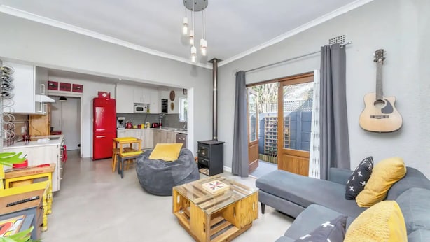 Un salon moderne avec un canapé, une table basse et une guitare accrochée au mur.
