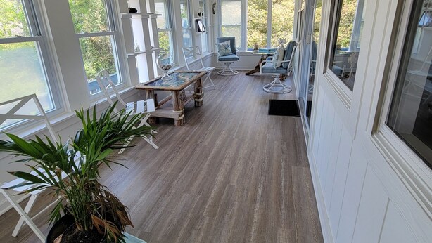 A sunlit room with large windows, wooden flooring, and a potted plant. - Something for everyone! Walk to beach/restaurant/parks/
shopping/entertainment (Nags Head)