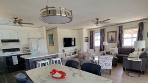 A modern kitchen with white cabinets, a central island, and a dining area with blue chairs. - Something for everyone! Walk to beach/restaurant/parks/
shopping/entertainment (Nags Head)