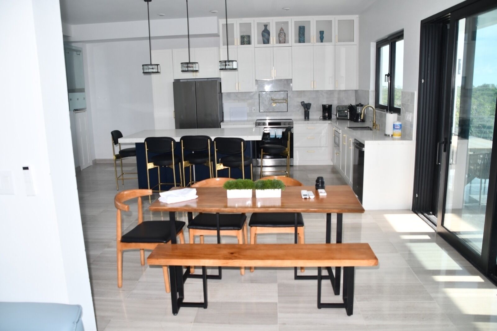Een moderne keuken met een eethoek, met een houten tafel, zwarte stoelen en hanglampen.