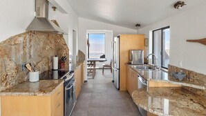 Een moderne keuken met granieten aanrecht, roestvrijstalen apparatuur en uitzicht naar buiten.