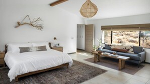 Een slaapkamer met een groot bed, een bank, een salontafel en een hanglamp.