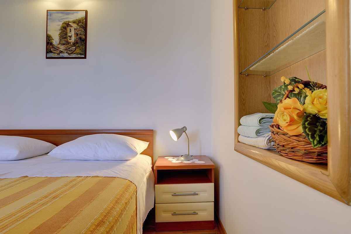 Une chambre d’hôtel avec un lit, une table de chevet avec une lampe, un miroir et un tableau accroché au mur.