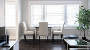 A dining area with a table and chairs, a TV, and a plant.