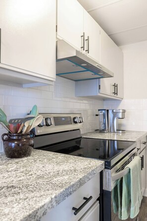 A kitchen with white cabinets, a stainless steel stove, and a coffee maker.