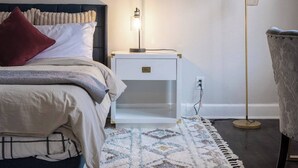 A bedroom with a bed, bedside table, lamp, and floor lamp.
