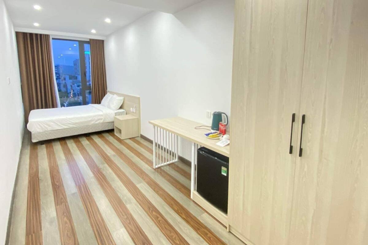 Ein modernes Hotelzimmer mit Bett, Schreibtisch, Kleiderschrank und Blick auf die Stadt.