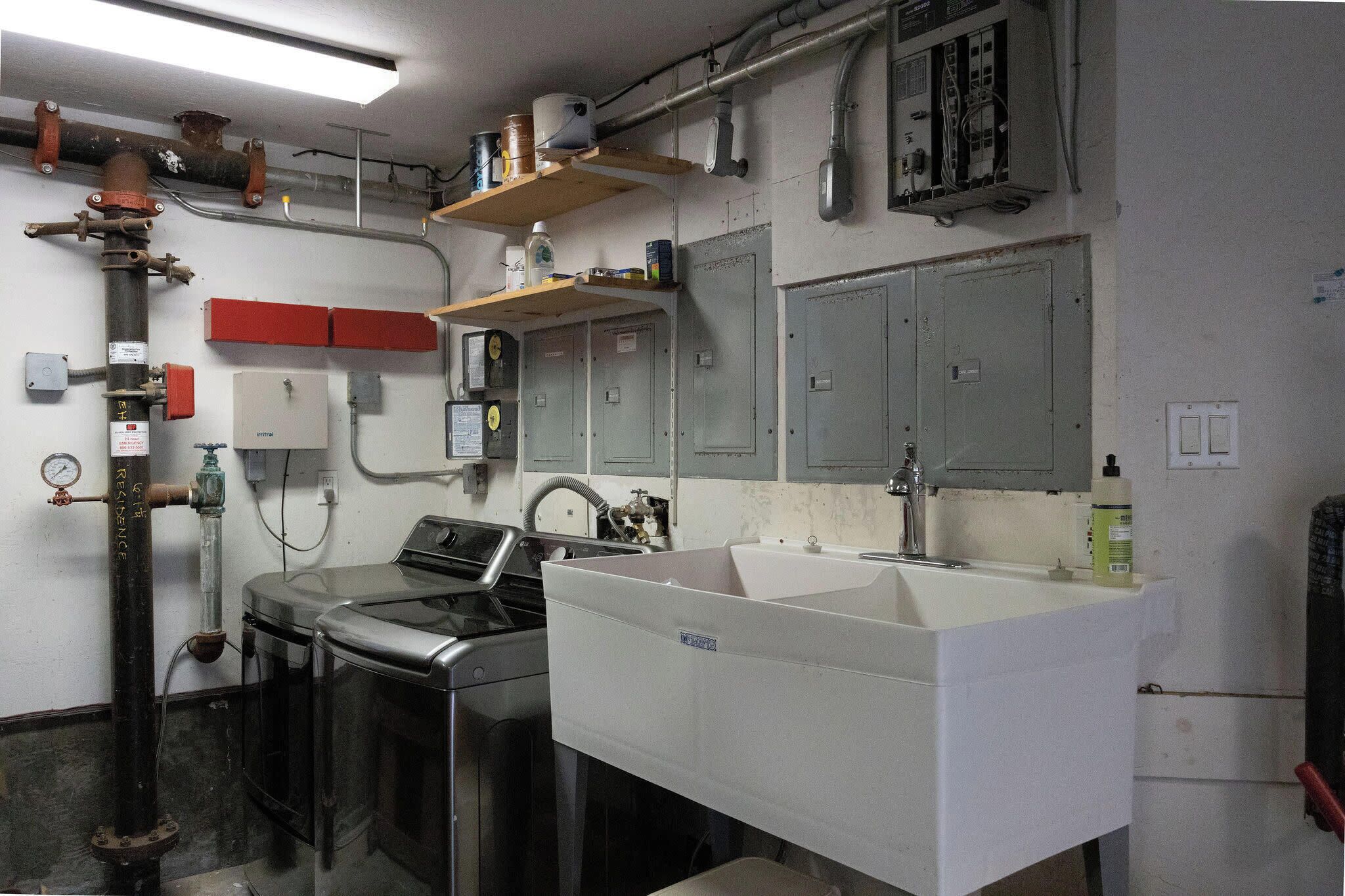 Una cocina con electrodomésticos de acero inoxidable, un lavamanos blanco y un armario rojo.