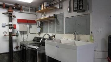 Una cocina con electrodomésticos de acero inoxidable, un lavamanos blanco y un armario rojo.