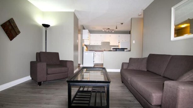 Ein Wohnzimmer mit Glastisch, zwei Sofas und einer Küche im Hintergrund.