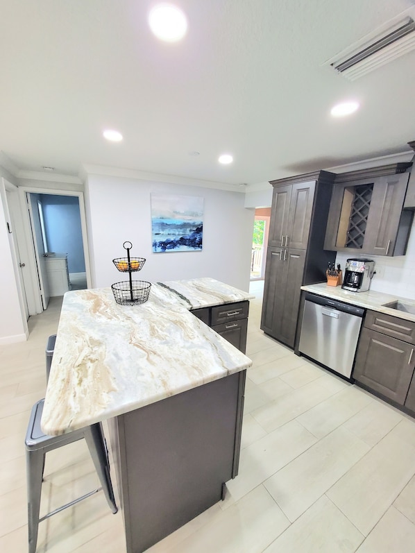 A modern kitchen with a marble countertop, stainless steel appliances, and wooden cabinets.